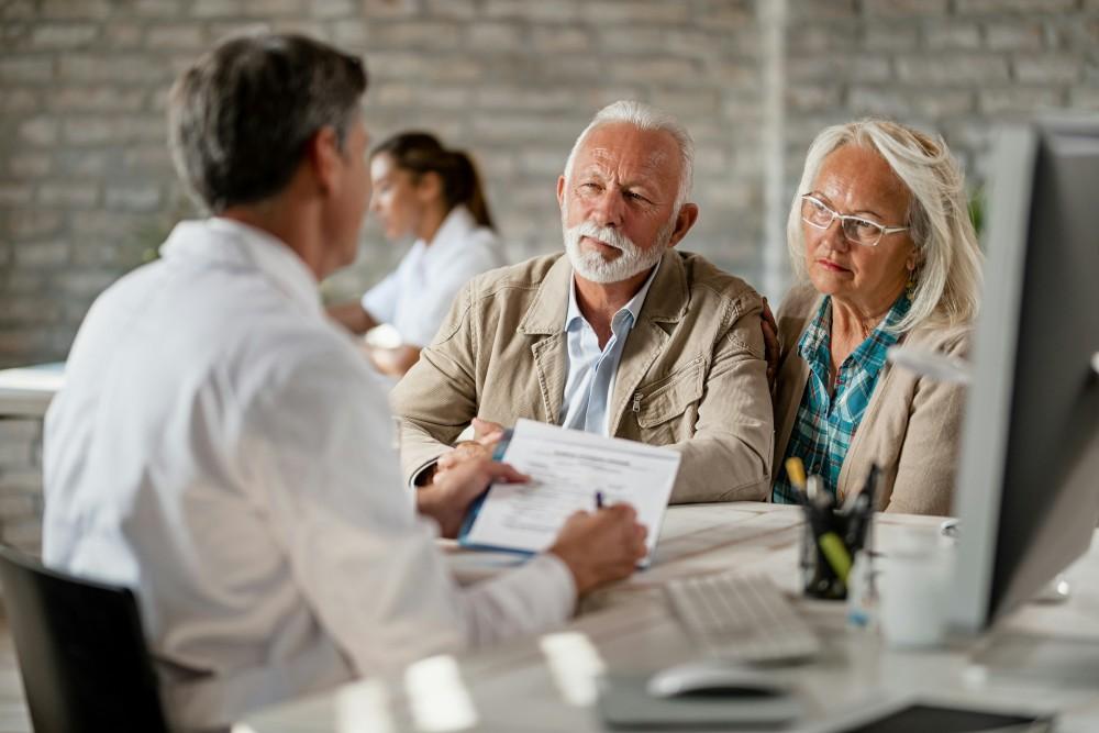 Courtier mutuelle senior expliquant les termes du contrat à un couple de seniors