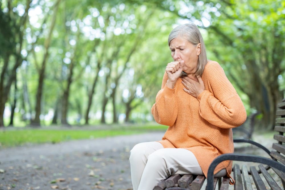 Femme sur un banc qui tousse et du mal à respirer