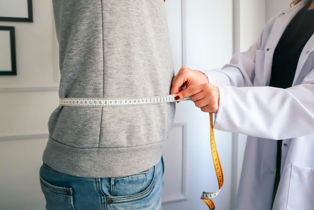 Médecin avec un mètre ruban prenant le tour de taille de son patient
