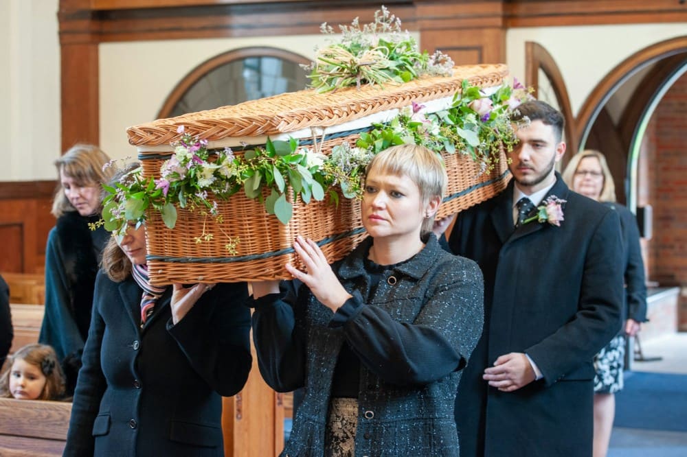 Famille qui porte un cercueil en osier