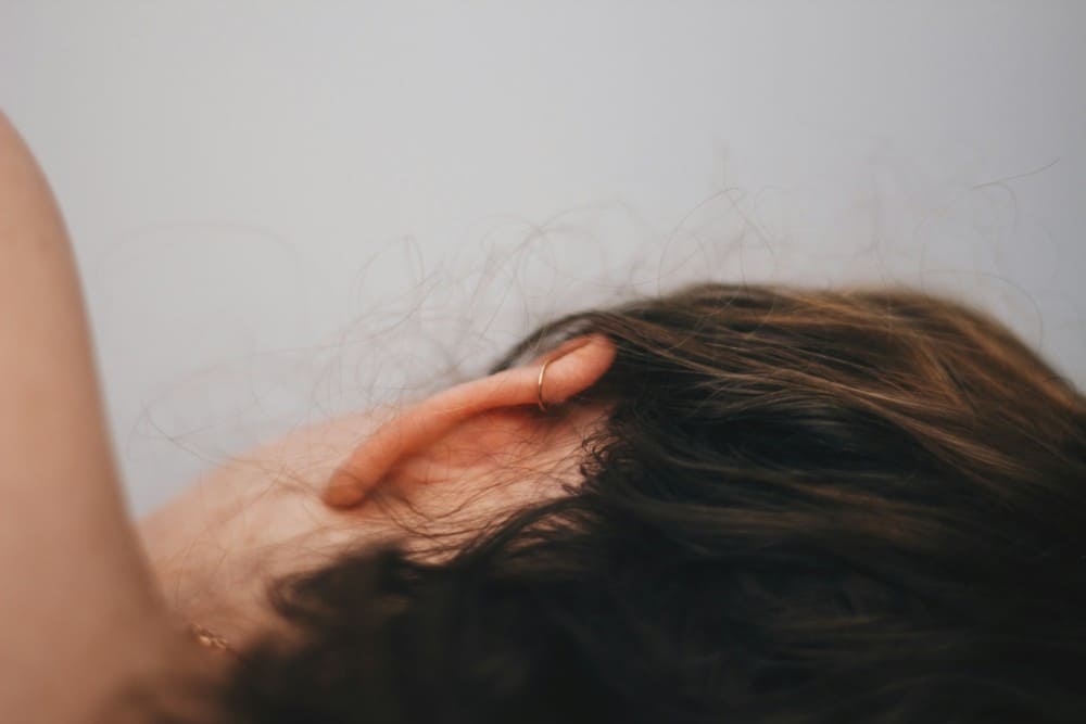 Femme allongée sur le côté montrant son oreille de dos