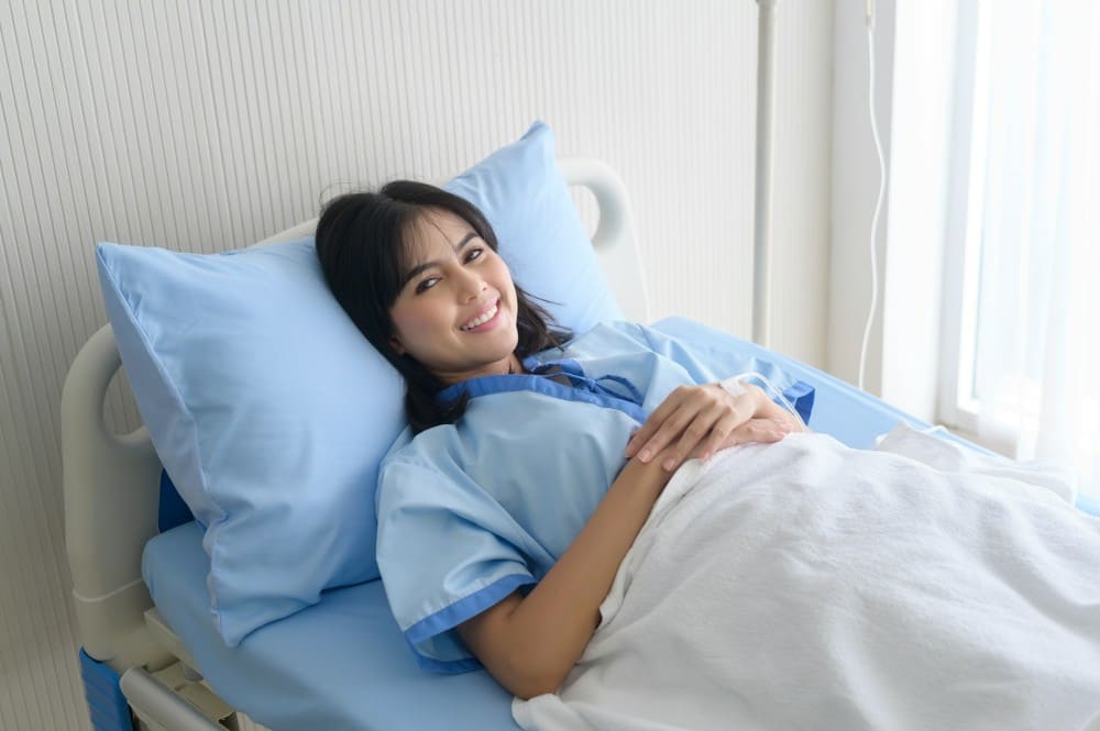 Femme dans son lit d'hôpital pour fistule anale