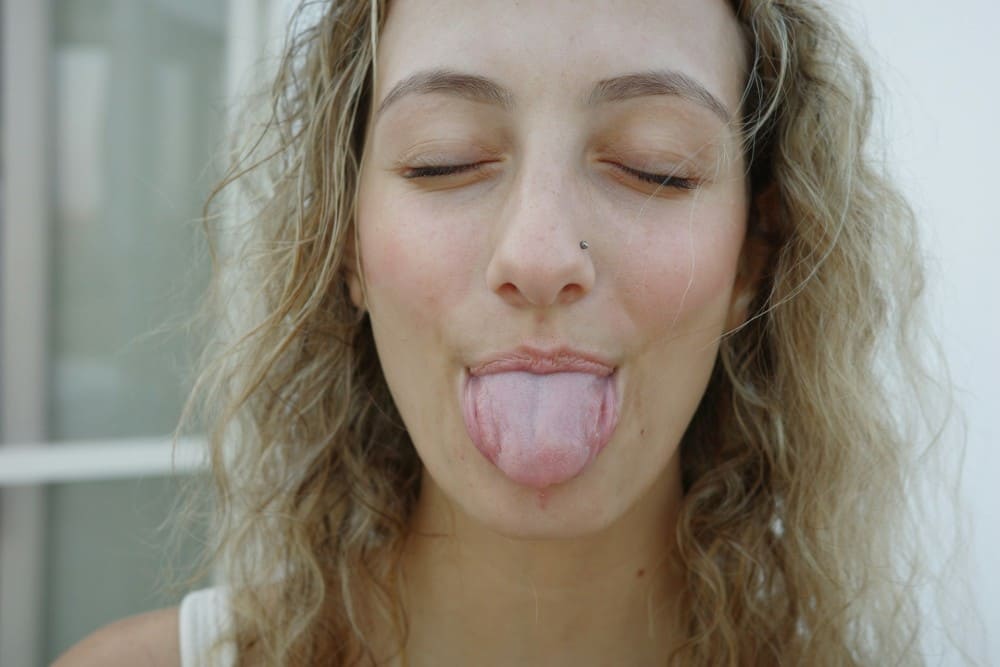 Femme aux cheveux longs ondules avec la langue blanche