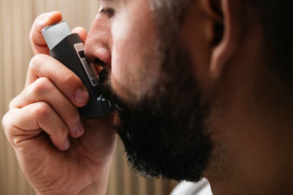 Homme barbu asthmatique qui prend de la ventoline