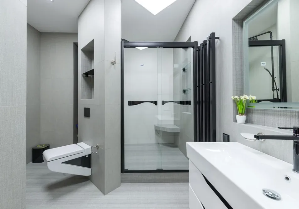 Douche moderne avec siège intégré, paroi vitrée, lavabo et toilettes suspendues.