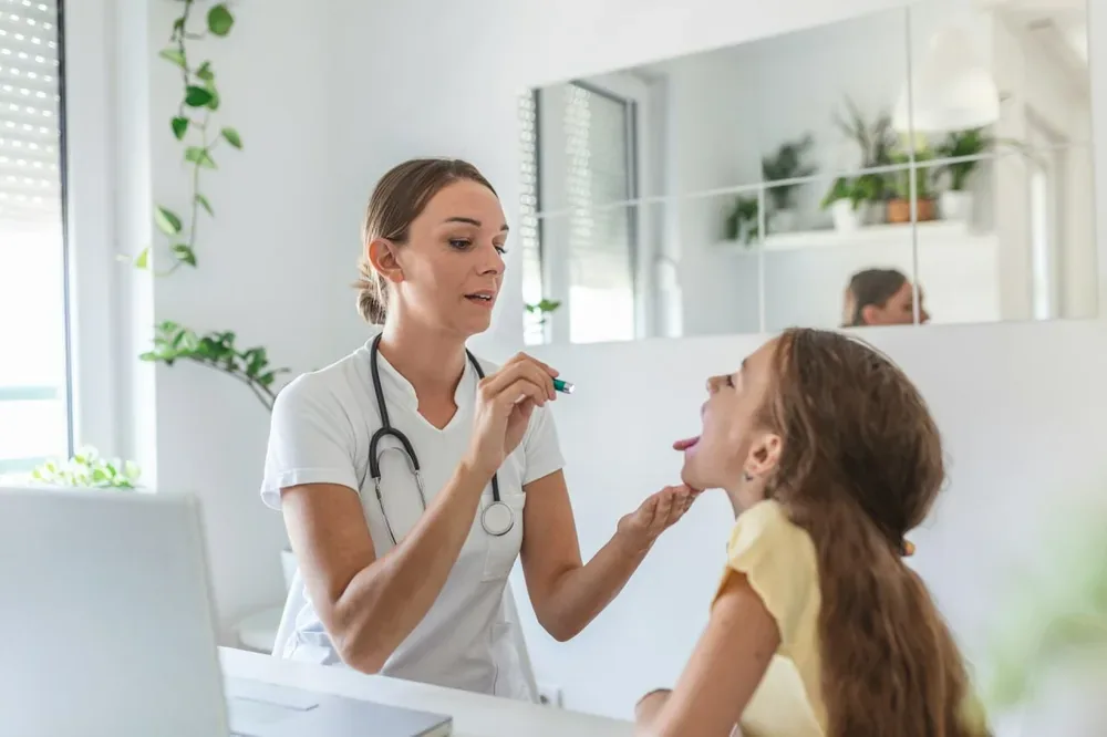 Professionnelle de sante examinant la bouche d'une patiente assise en consultation