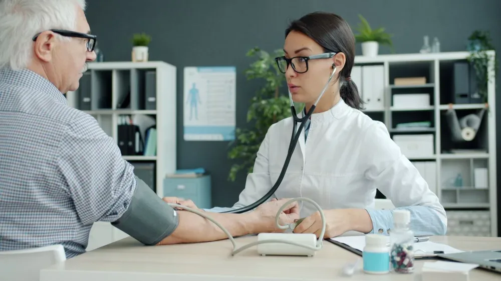 Médecin prenant la tension artérielle d'un homme âgé en consultation