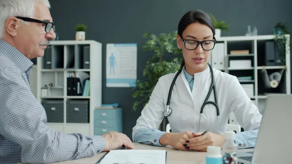 Médecin en consultation avec un patient âgé dans un cabinet médical.