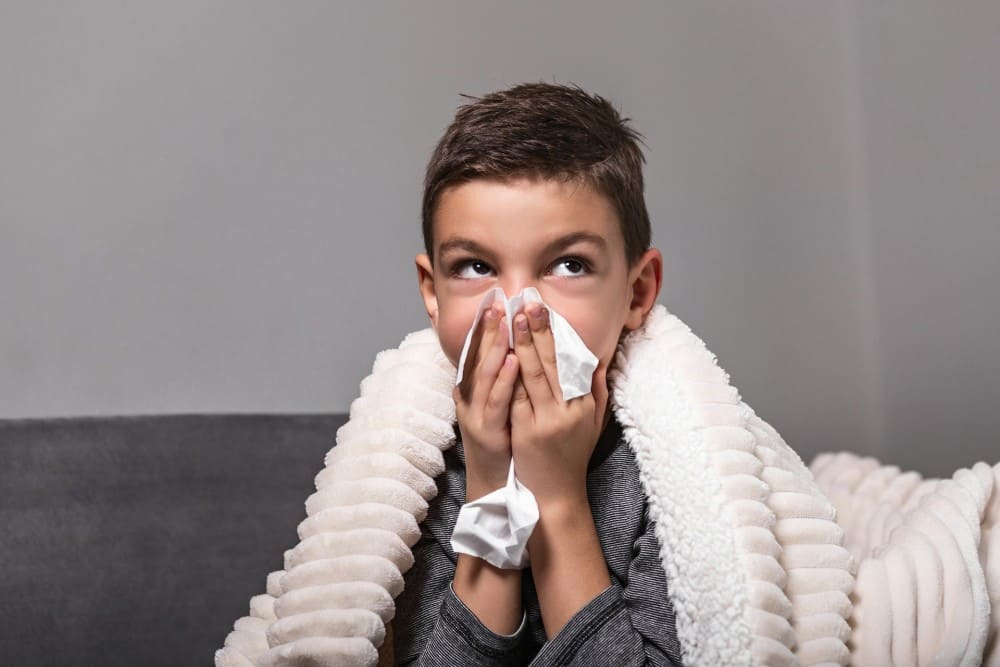 Petit garçon qui se mouche faisant des allergies