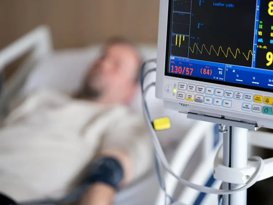 Défibrillateur implanté : personne allongée près d'un moniteur médical, avec le visage flouté.