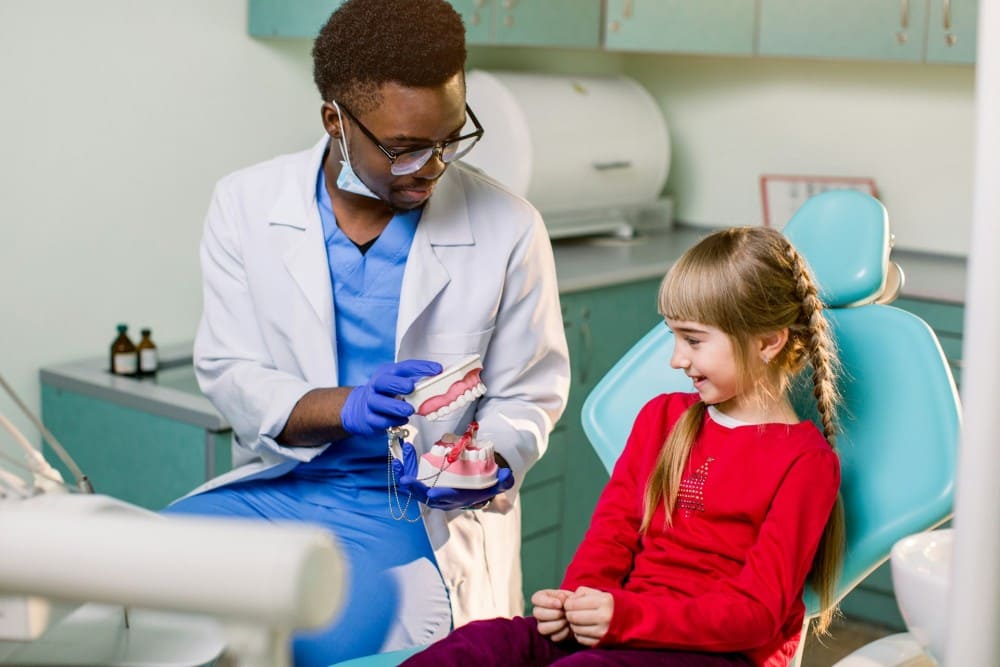Enfant avec dentiste qui lui montre comment utiliser la brosse  à dents