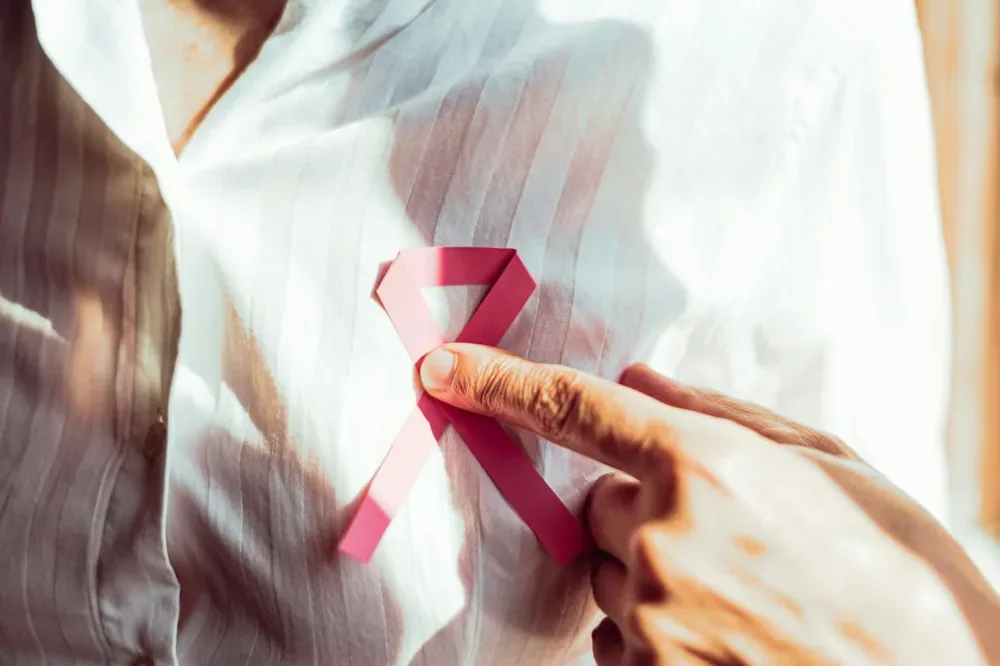 Un homme porte un ruban octobre rose épinglé sur sa chemise.