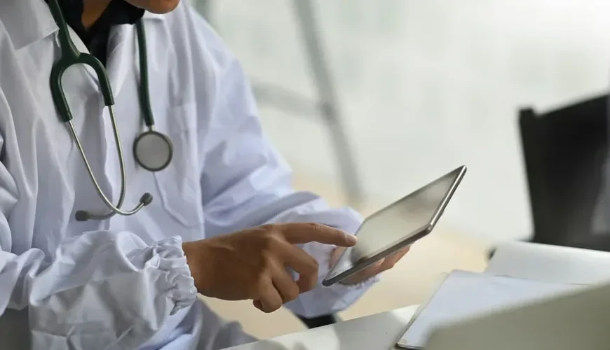 Logiciel oncologue : un médecin utilise une tablette dans un espace de travail médical.