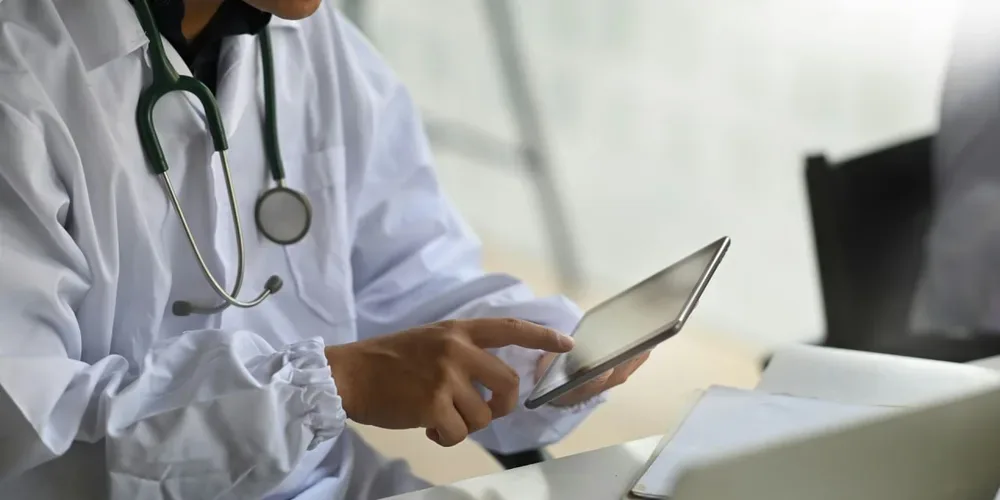 Logiciel oncologue : un médecin utilise une tablette dans un espace de travail médical.