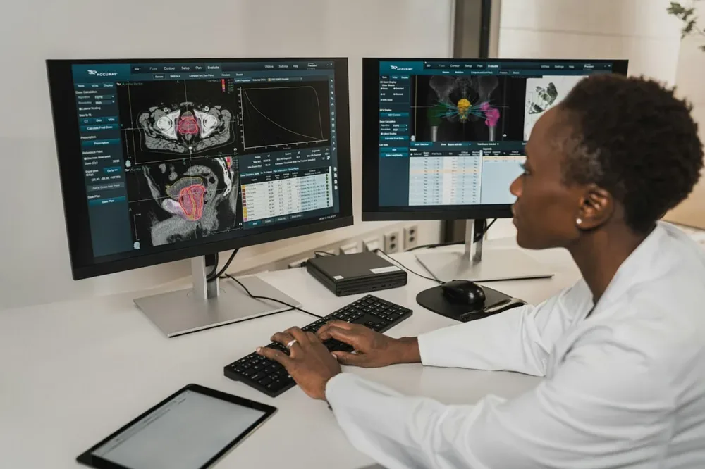 Logiciel oncologue : une personne saisit des informations sur des moniteurs médicaux.