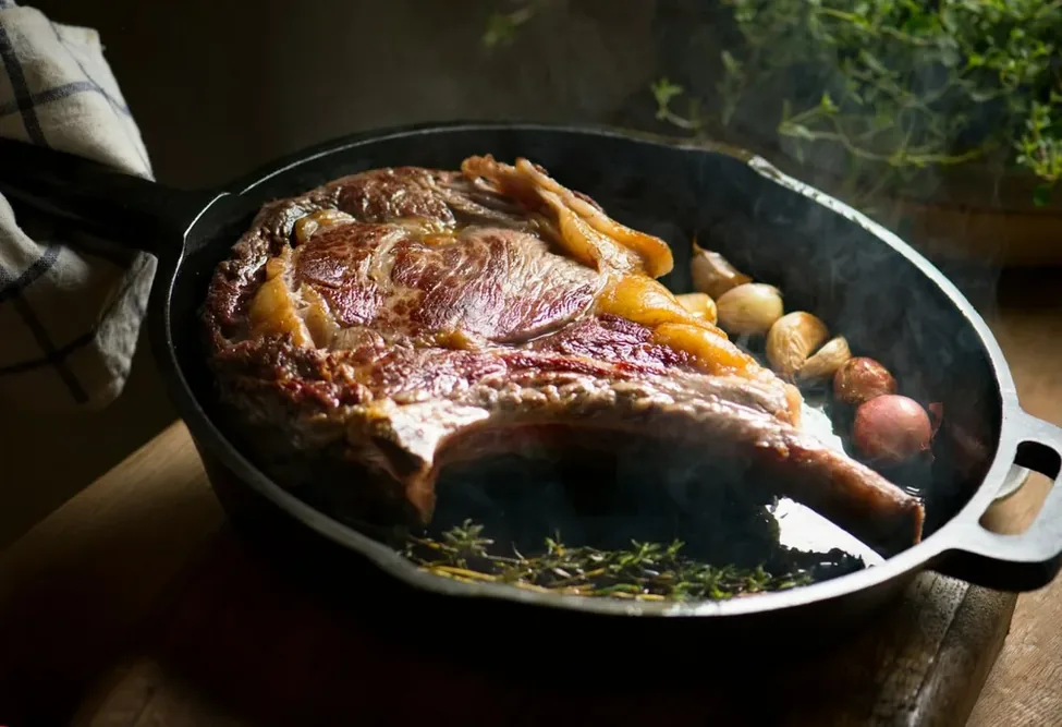 PFAS : une côte de bœuf cuit dans une poêle avec des légumes.